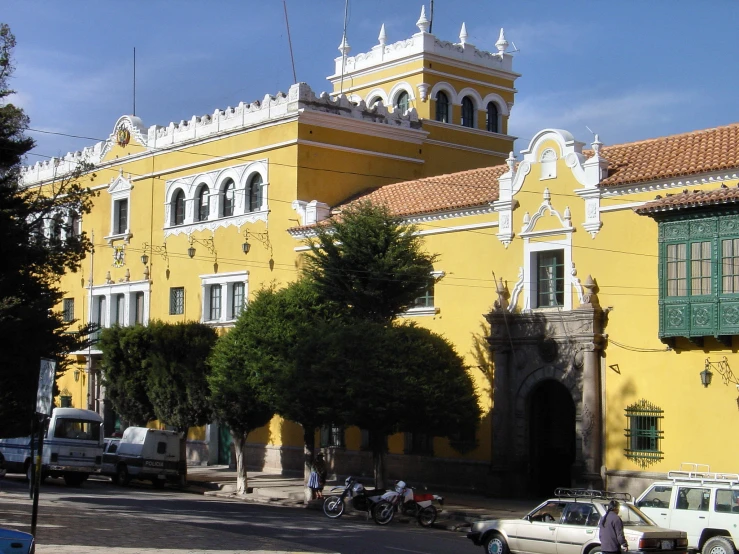 a building with large clock and windows stands tall over several vehicles