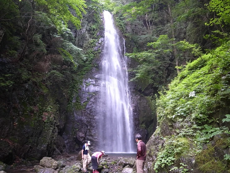 two men stand in front of a waterfall