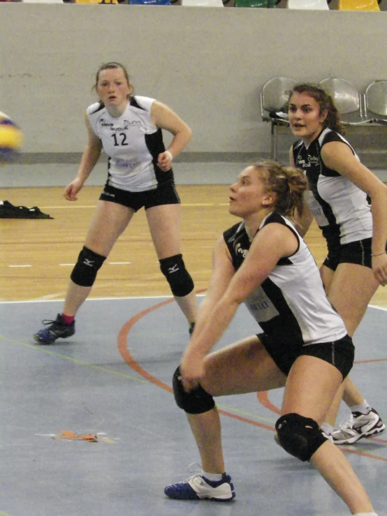 two girls in volleyball uniforms playing soccer on a court