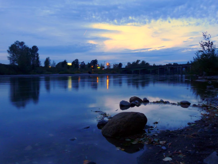 the reflection of lights and a large rock in the lake