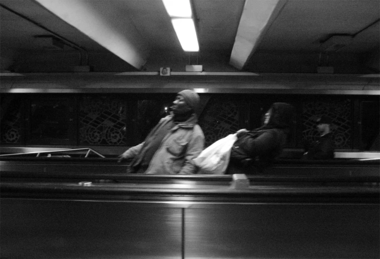 a man and woman are standing at the bottom of an escalator