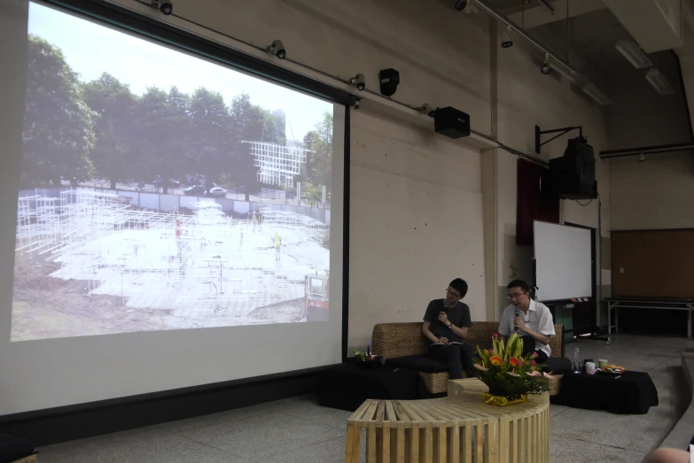 two people sitting in front of an outdoor projection screen