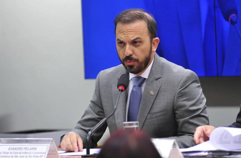 a man sitting at a table speaking into a microphone