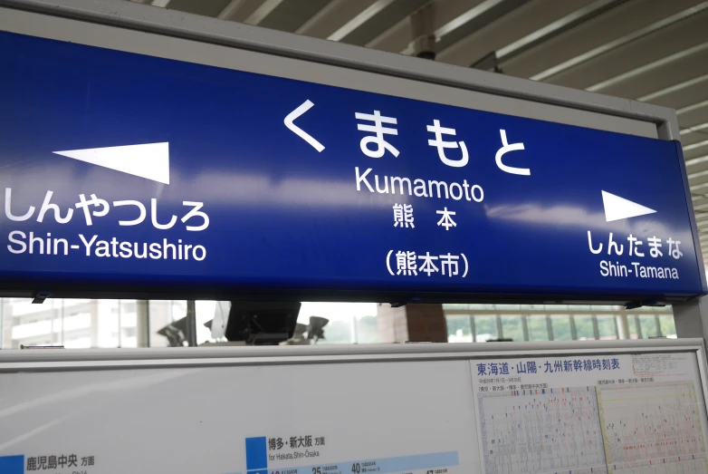 a blue directional sign sits in front of a window