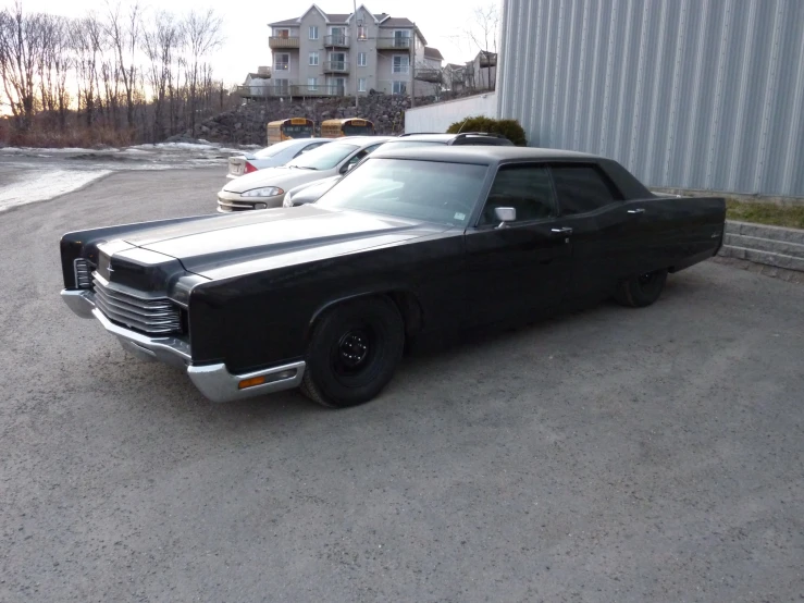 an old black car is parked in the parking lot