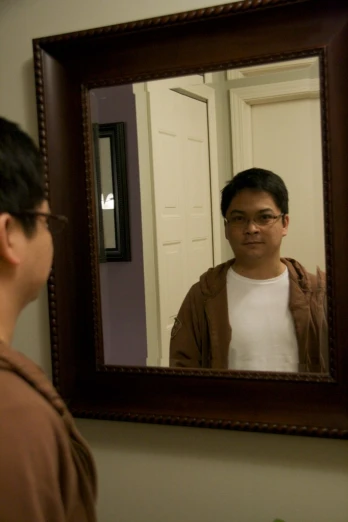 a man wearing glasses looking in a mirror