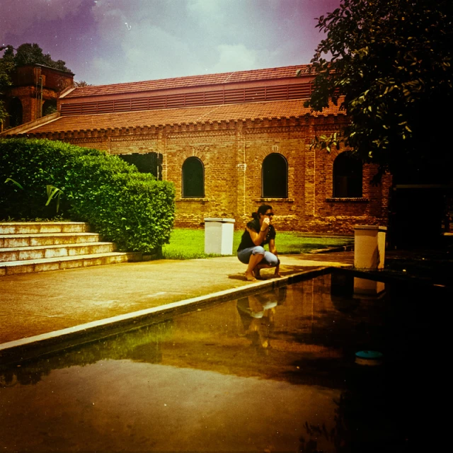 a girl with a hat kneeling in front of a building