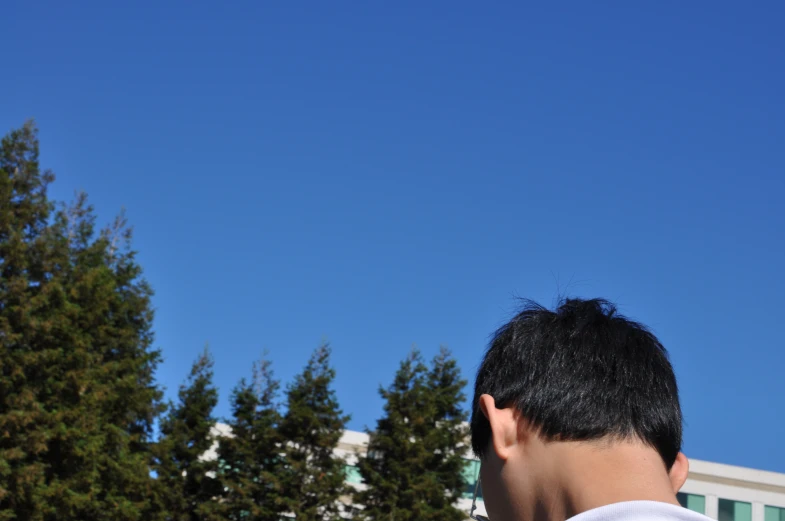 young man looking up at the sky with building in background