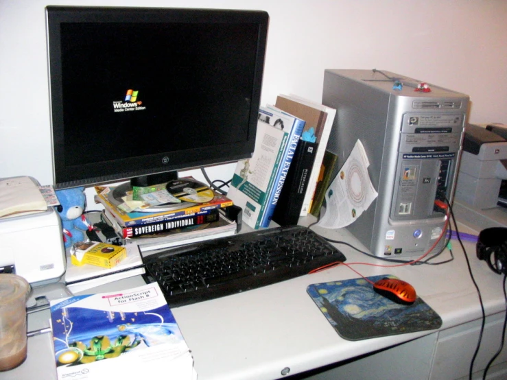 the computer is set up beside a book collection