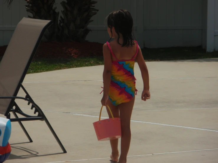 little girl in colorful swimsuit walking along tennis court