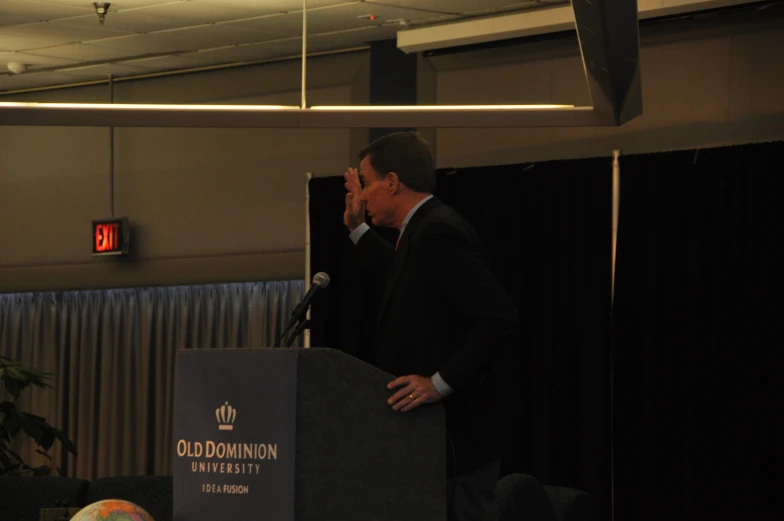 a man standing behind a podium with his mouth open