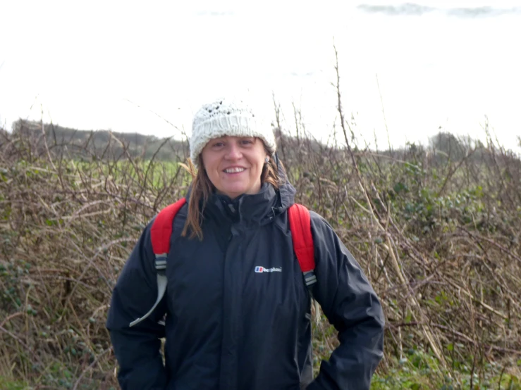 a woman wearing a backpack is standing in the brush