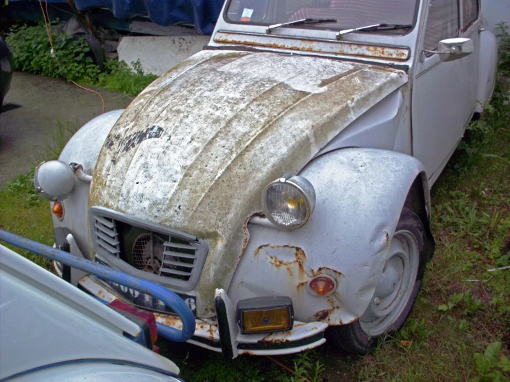 an old white car is rusted off and rusty