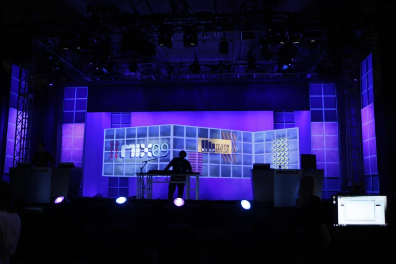 a purple stage with purple lights and someone at a desk