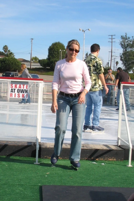 a woman on an ice rink wearing blue jeans and a pink sweater