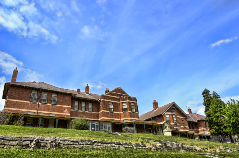 a red brick building stands on top of a green grassy hill