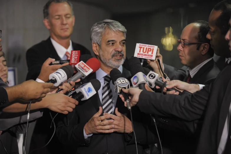 there is a man surrounded by microphones holding a sign