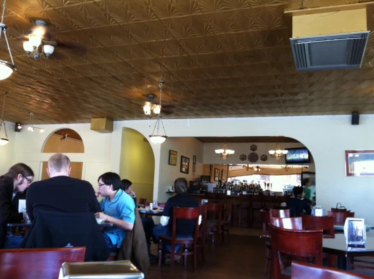 a view of an inside restaurant, the people sitting at tables look out into the dining room