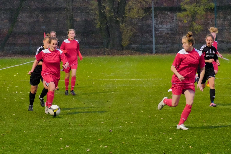 girls are running around the field playing soccer