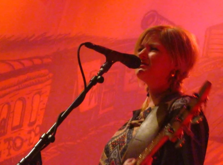 a woman singing into a microphone on stage