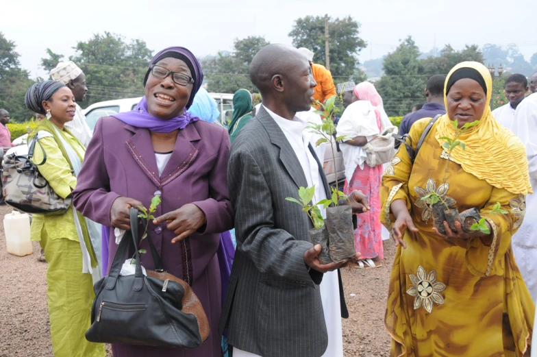 a group of people holding small tree saplings