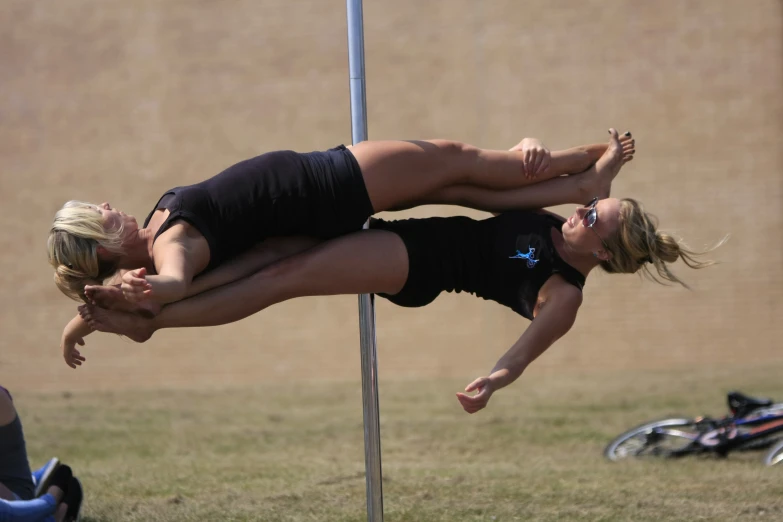 two women on pole performing a stunt on a field