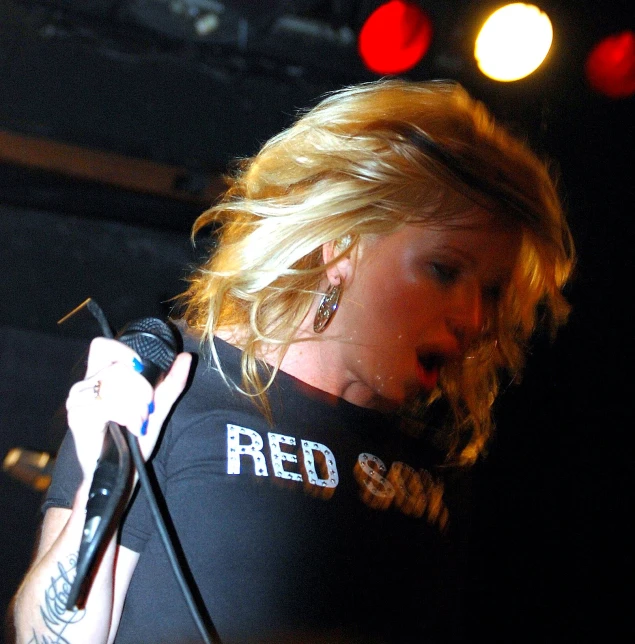 a beautiful blond woman wearing a black shirt holding a microphone