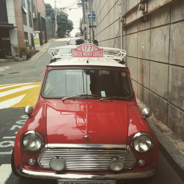 red and white vintage car on city street with buildings