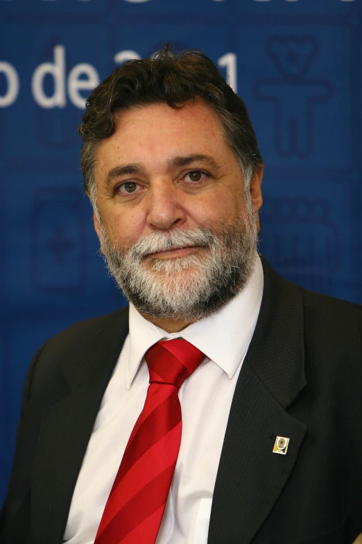 a man wearing a red tie standing in front of a blue sign