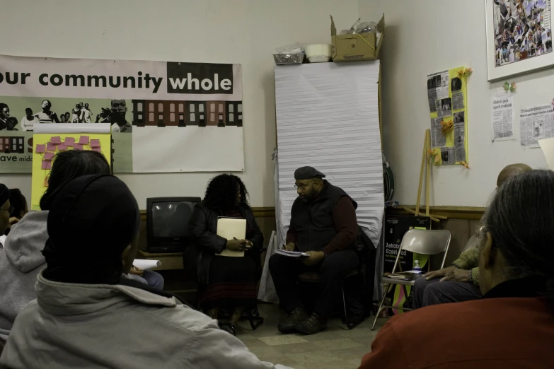 group of people in small white room looking at papers