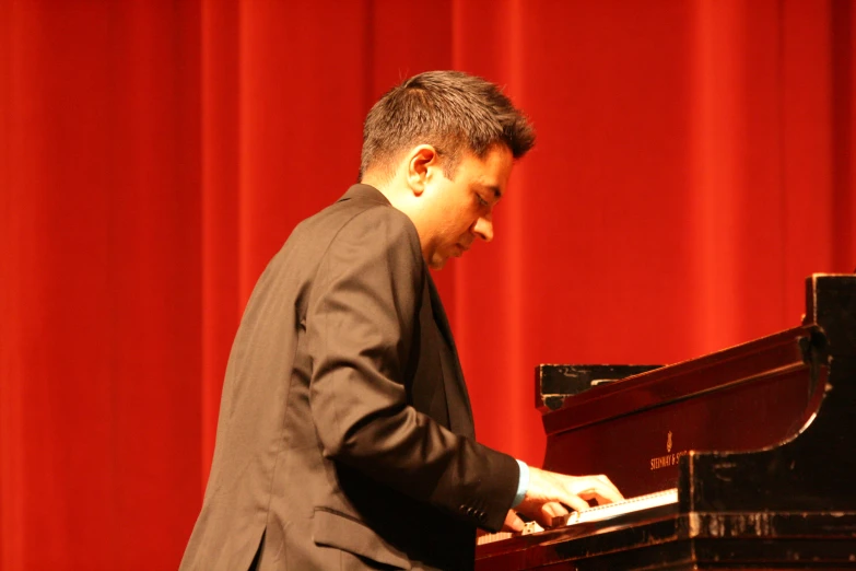 a man in a black suit and jacket playing the piano