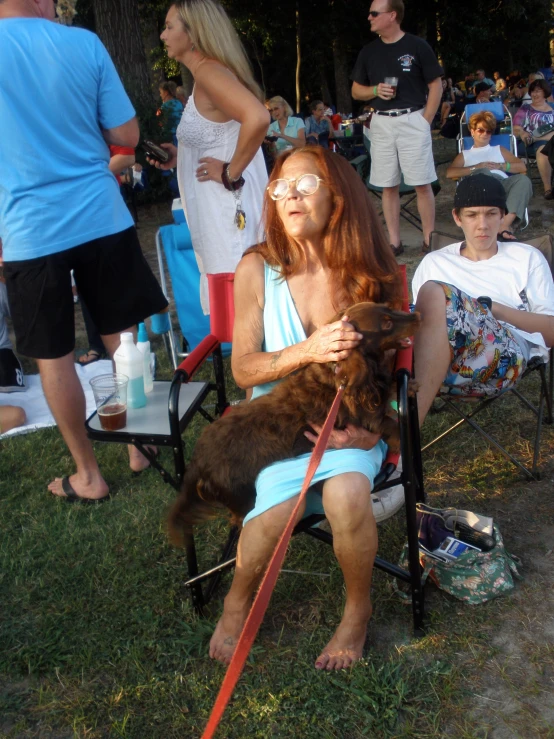 a woman with red hair sitting next to a dog in front of a crowd