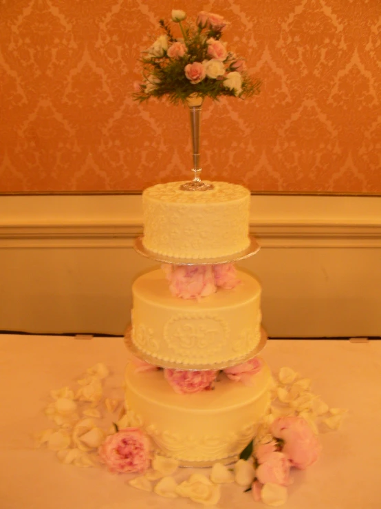 three layered cake is on top of a table with flowers