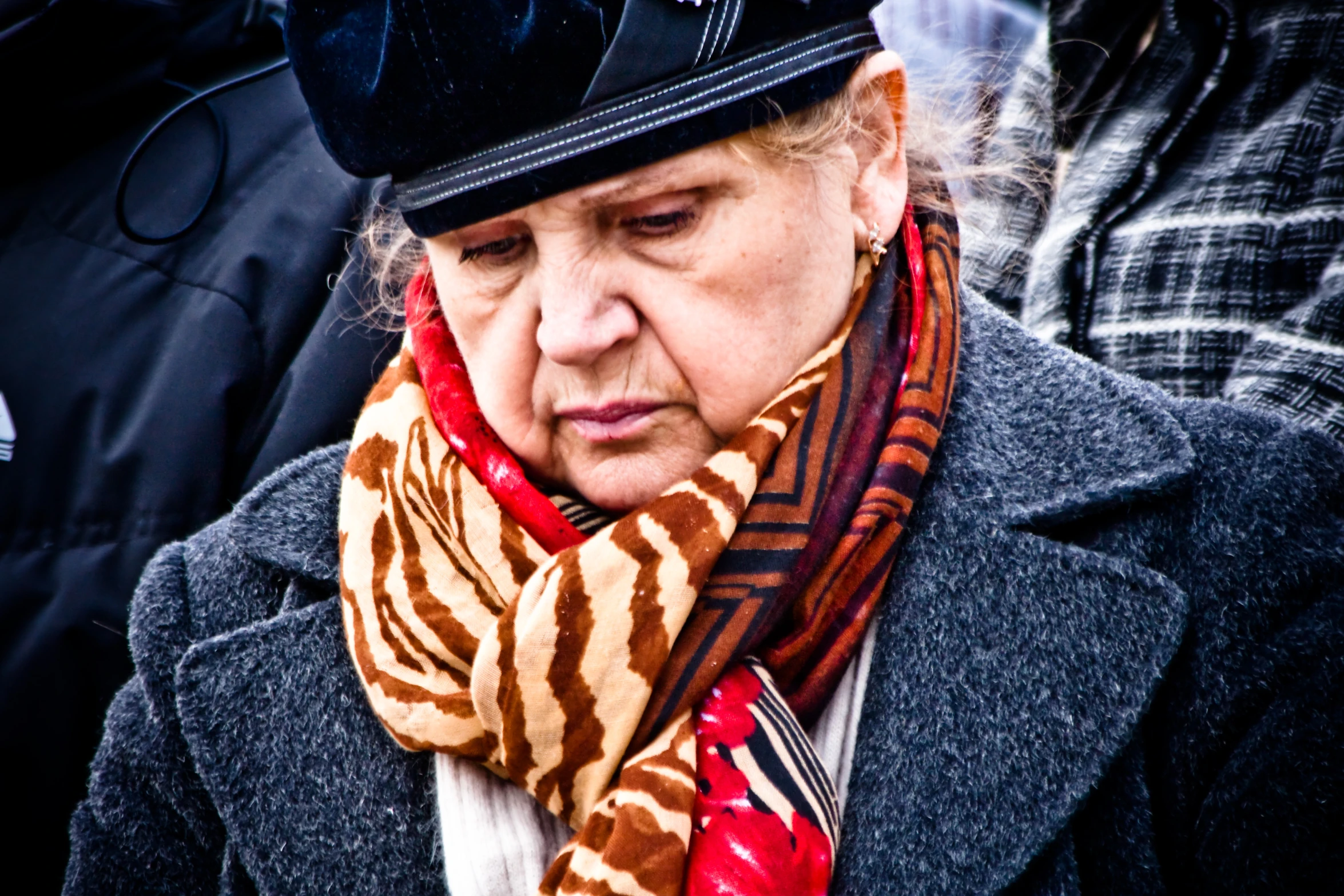 an old woman in a black hat and striped scarf