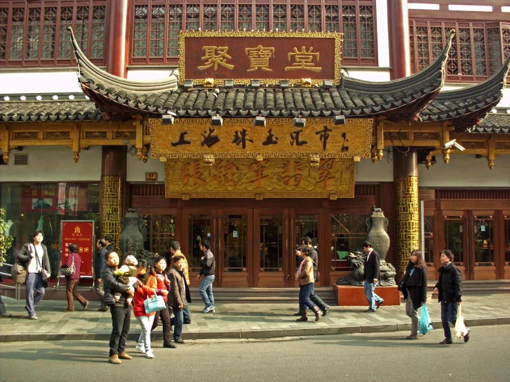 a group of people standing outside of a chinese building