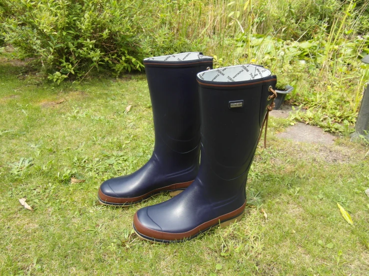 two black rain boots are lined up in the grass