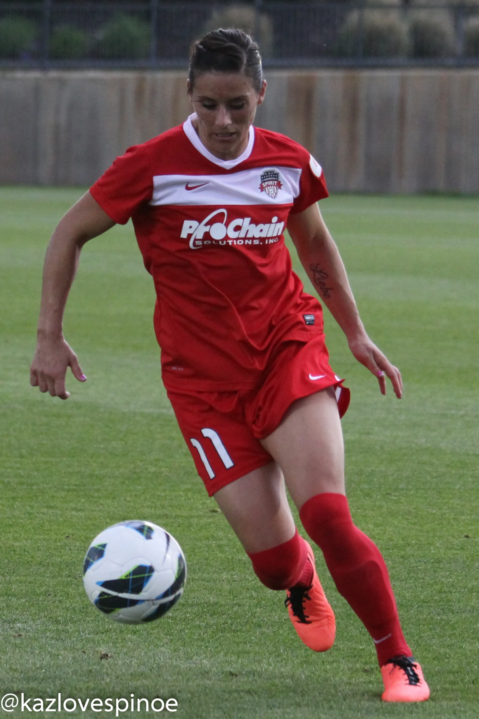 girl in red soccer uniform kicking a soccer ball