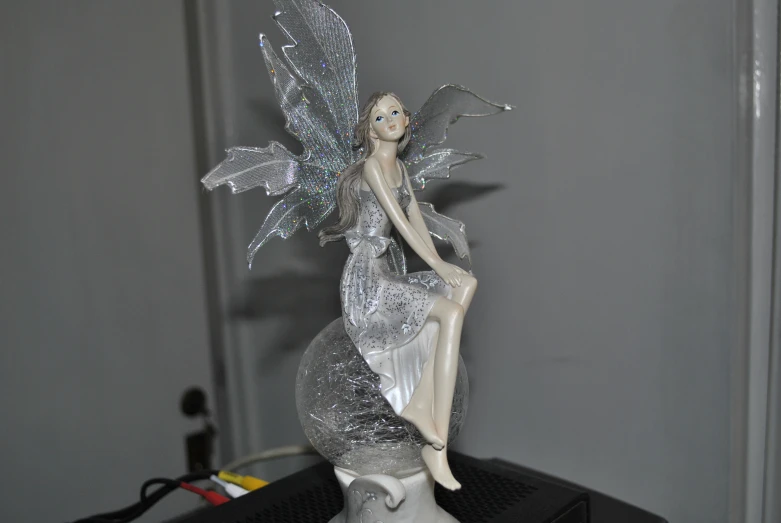 a silver fairy statue holding up a bird