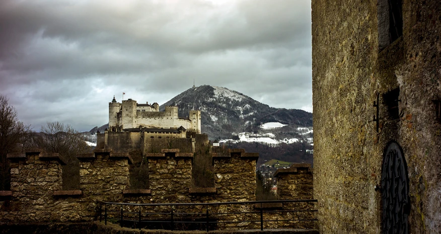 an old, stone castle with a snowy mountain in the background