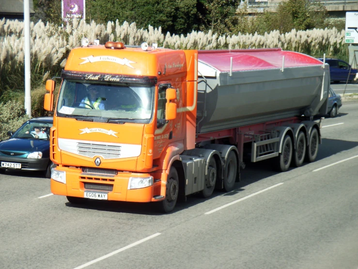 an orange truck with a water tanker trailer driving down the road