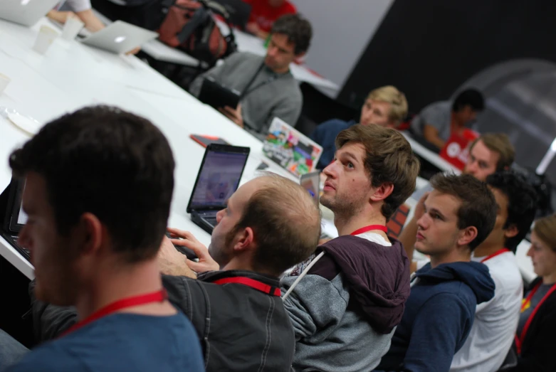 a man looking up at his laptop in a crowded room