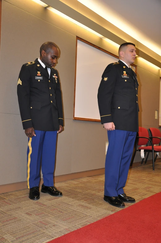 two uniformed men in uniforms in front of a screen