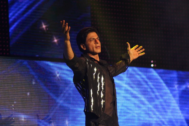 a man in black shirt waving at someone on stage