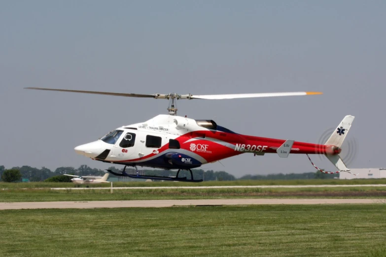 red and white helicopter preparing to land on a runway