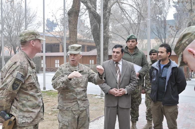 three military men talking with one of them standing