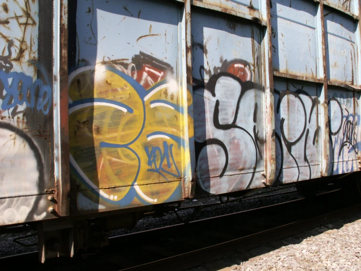 a rusty train covered with graffiti in the middle of the day