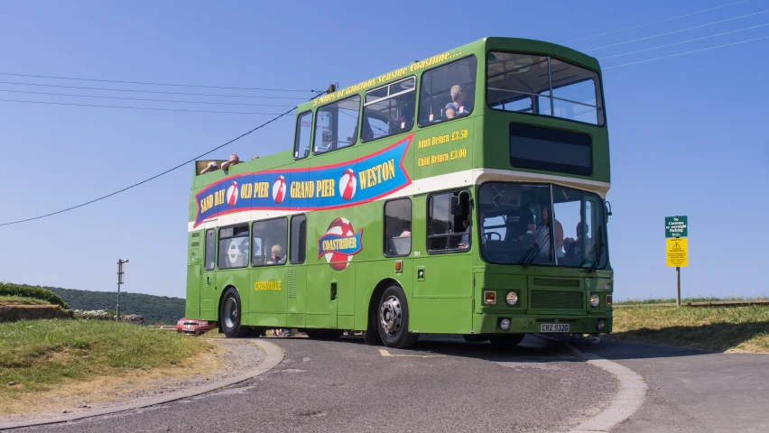 a green double - decker bus driving down a street