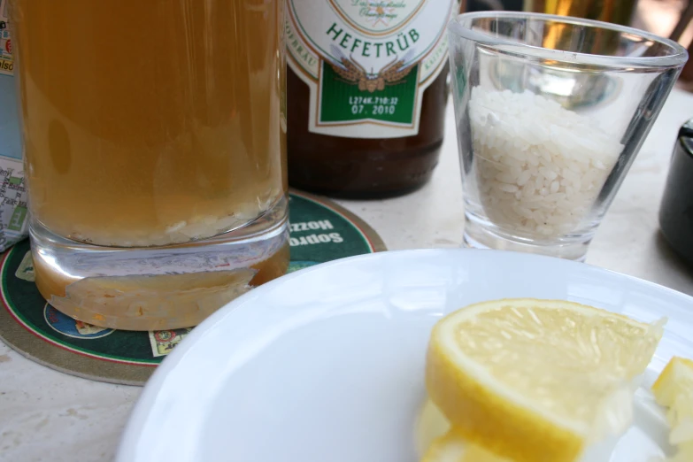 a plate with a slice of lemon on it near some beer bottles