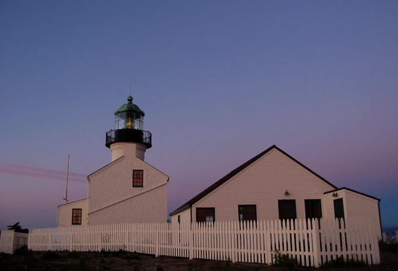 the lighthouse is near a white picket fence