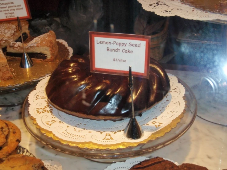 this display case holds a lemon - poppy seed bundt cake and cookies